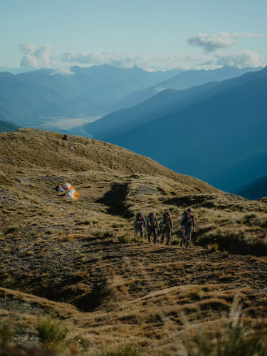 Group of hikers on a mountain trail with a scenic view of mountains and sky.